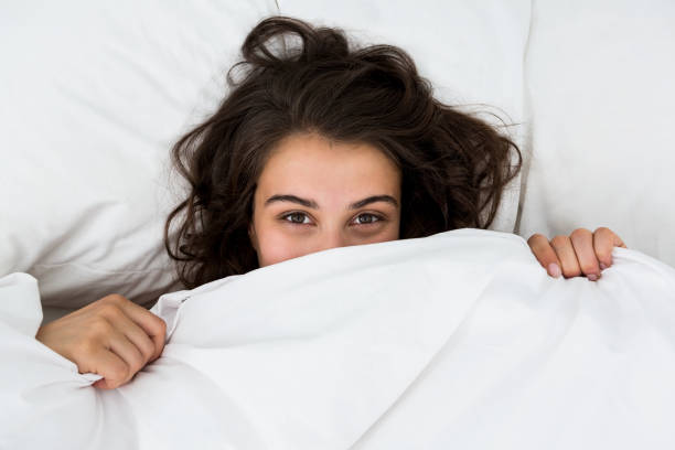 istock Woman hiding under blanket on bed 660540014