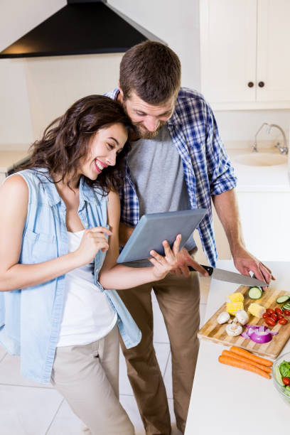 istock Woman using digital tablet and man chopping vegetables 660544134