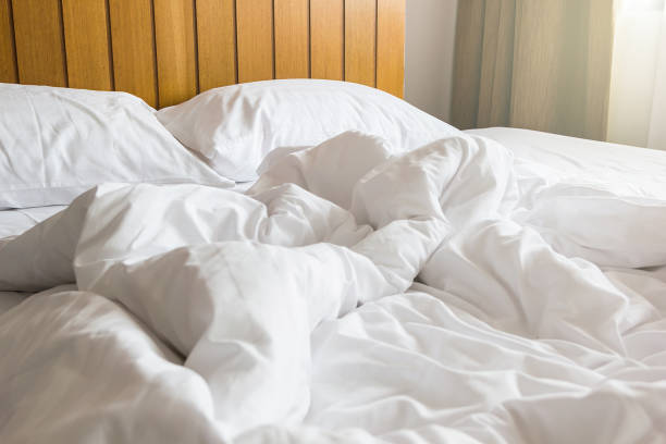 istock white pillow and blanket with wrinkle messy on bed in bedroom with lighting upper left side, from sleeping in a long night winter. 660550488