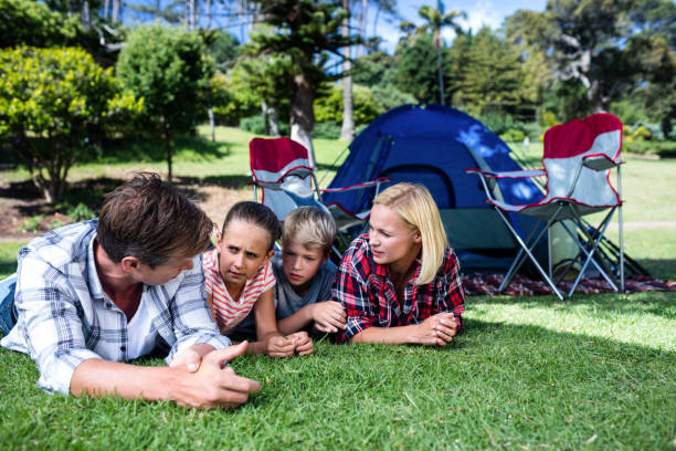 Family talking to each other while lying on grass outside the tent