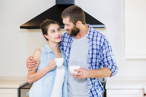 istock Young couple holding cup of coffee in kitchen 660572606