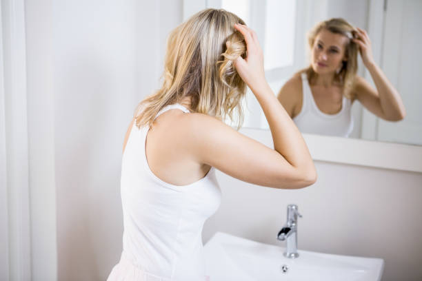 istock Young woman checking her hair in bathroom mirror 660573464