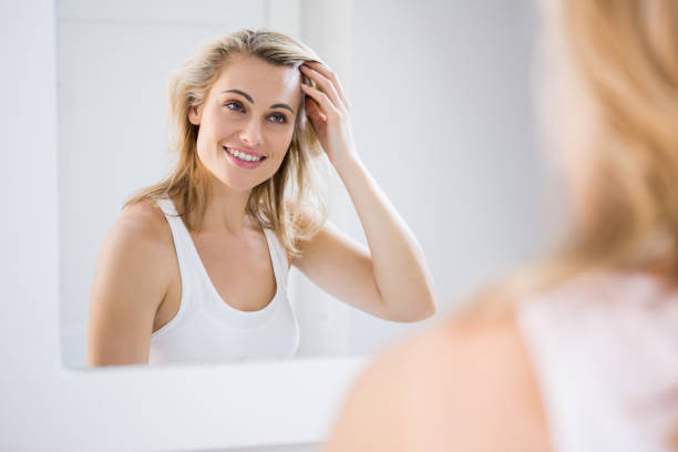 istock Young woman checking her hair in bathroom mirror 660573474