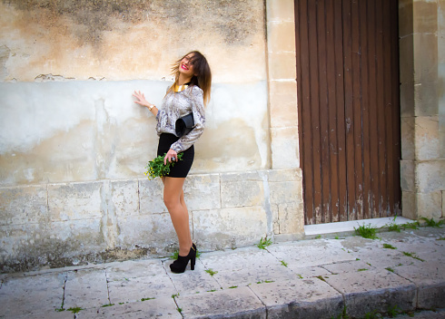 Chic Young Woman in Miniskirt; Old Wall Background