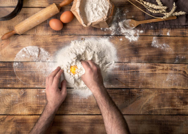 istock Man cooking dough on wooden table in bakery 660582674