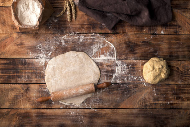 istock Roll out dough with rolling pin and flour on a wooden table, top view 660582716