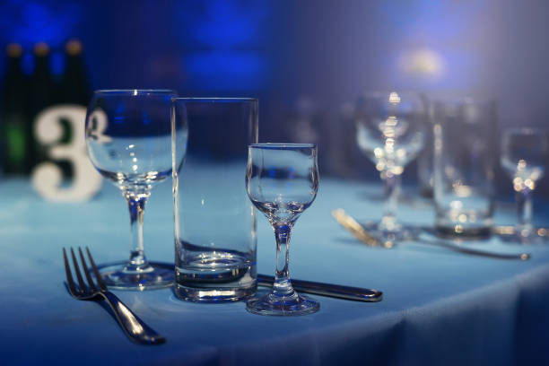 istock Table setting, empty wine glasses, piles. Banquet room in a blue haze. 660605996