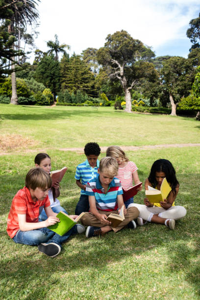 istock Children reading book in the park 660607134