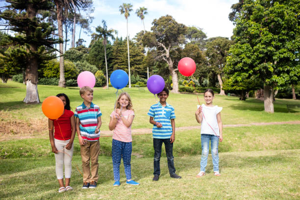 istock Children standing with balloons in the park 660610308