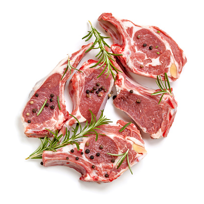 Raw lamb cutlets, top view, isolated, with rosemary and peppercorns.