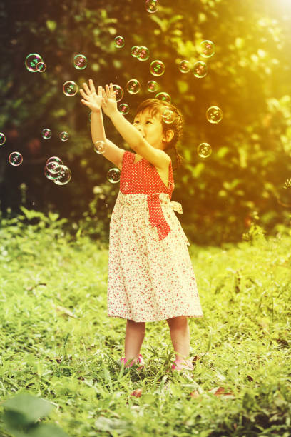 istock Asian girl catches soap bubbles on nature background. 660617526