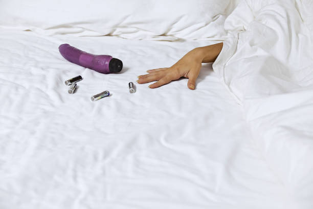Woman's hand reaching for dildo in bed stock photo