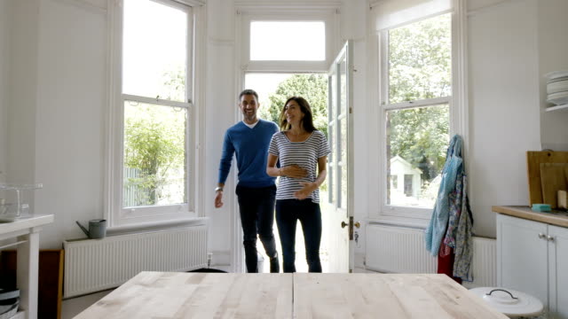 Pregnant couple entering kitchen from backyard