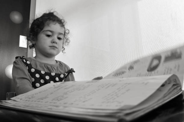 Portrait of a young girl sits on table with stack of books
