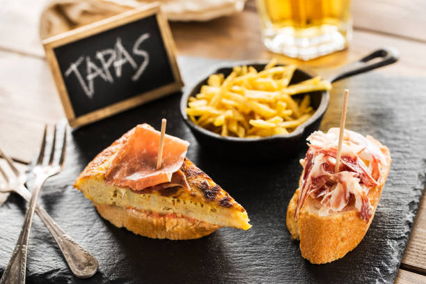 Spanish tapas Delicious spanish tapas and beer served on a wooden table. tortilla de patatas stock pictures, royalty-free photos & images