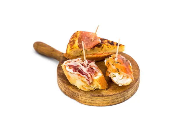 Typical spanish pub food pincho. Isolated on white background on a wooden board.