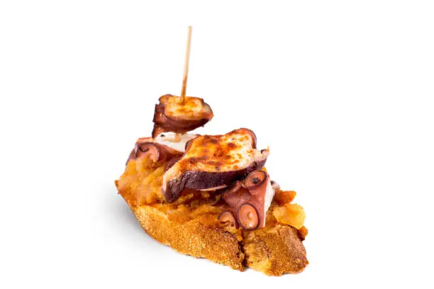 Typical spanish food. Pincho with galician octopus on slice of bread. Isolated on white background.