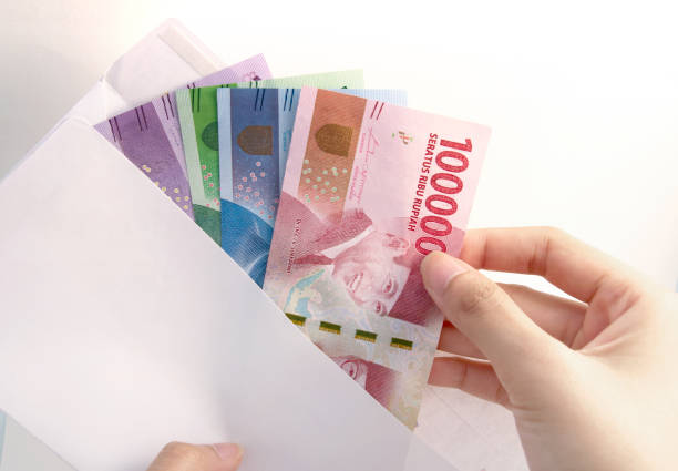 main de femme et l’argent de la roupie d’indonésie sur enveloppe blanche - indonesian currency photos et images de collection