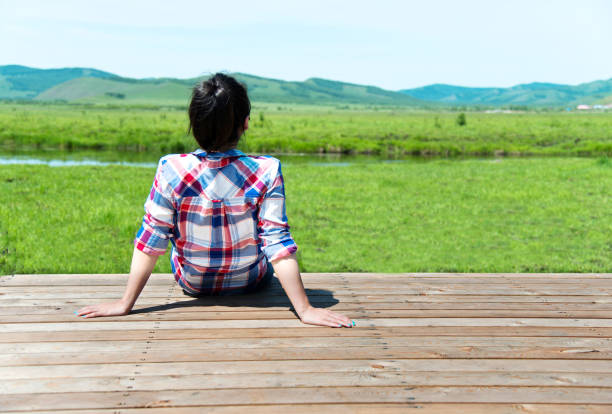 istock Woman looking away while sitting on wooden platform 660644172