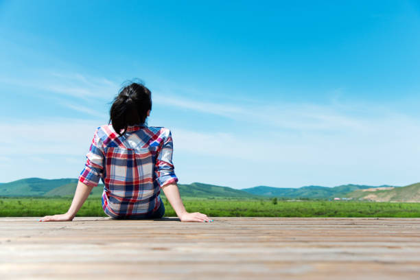Woman looking away while sitting on wooden platform