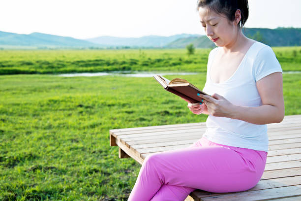 istock Young woman reading in the nature 660647652