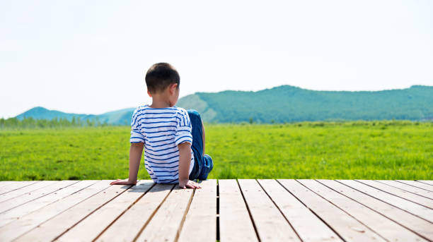 Boy sitting alone on deck of nature