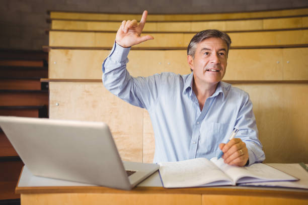 istock Confident professor raising his hand in classroom 660654946