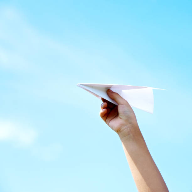 istock Boy hand holding a paper plane against the sky background 660655922