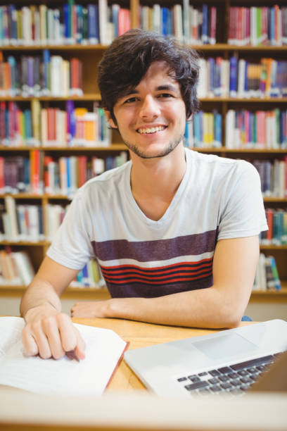 istock Happy young student sitting at desk reading a book 660656214