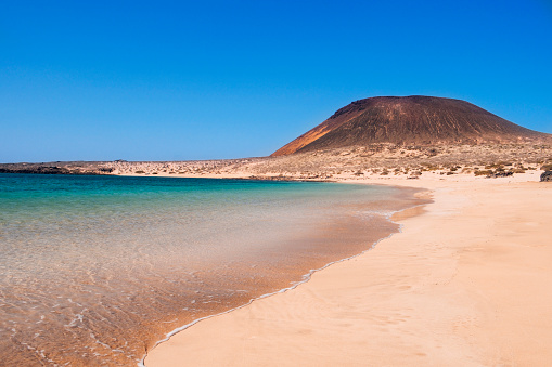 a view of La Francesa Beach in La Graciosa island, in the Canary Islands, Spain, with the Montana Amarilla mountain in the background