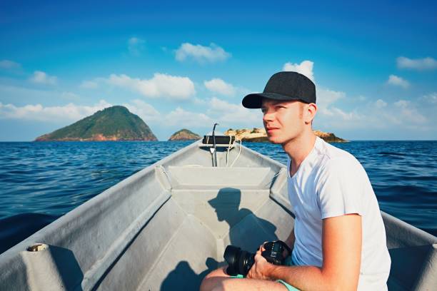 Idyllic vacation. Young photographer with dslr camera traveling by boat.
