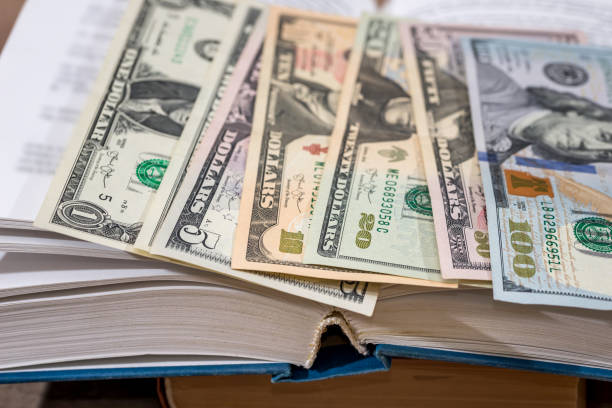 istock us 100 dollar in book on desk. 660667518