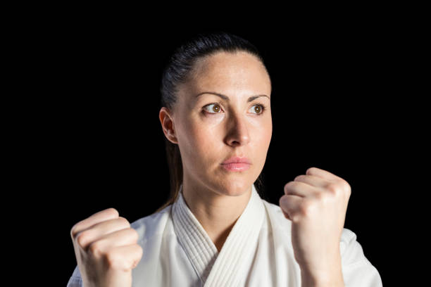 Female fighter performing karate stance on black background
