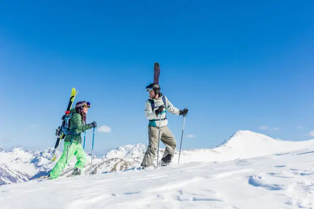 Man and woman backcountry skiers ascending mountain