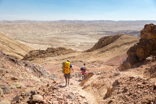 istock Couple tourists backpackers walking descending  desert stone mountain trail. 660700184