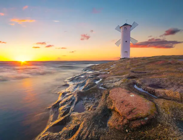 Beautiful sunset over a windmill-shaped lighthouse, Swinoujscie, Poland"t
