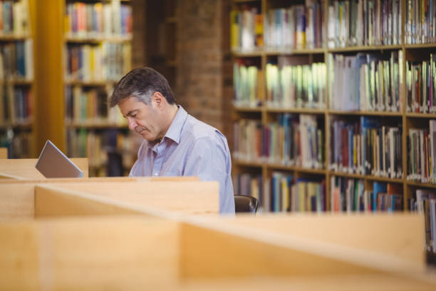 istock Professor sitting at desk using his laptop 660707604