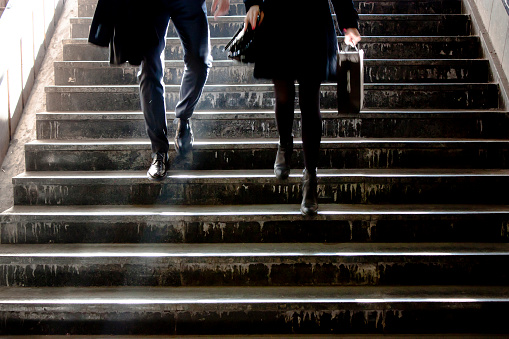 Blurry young business  man and woman going down the subway stairs towards the camera , shot from waist down in the center of Belgrade, Serbia