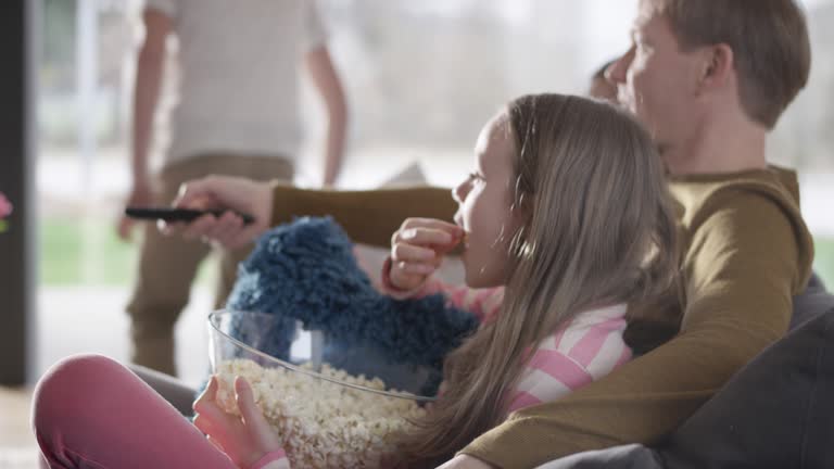 Family eating popcorn and watching TV