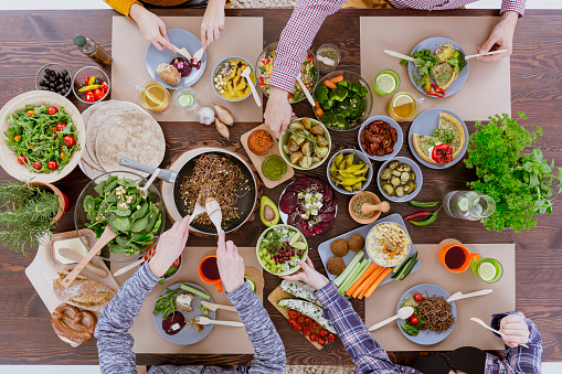 Group of friends on a colorful vegetarian lunch by the wooden table
