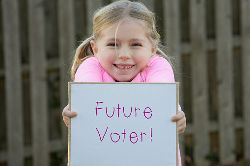 edad escolar adorable niña con futuro votante cartel photo