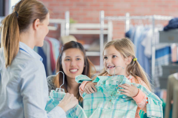 Happy young shopper Young Caucasian girl shops with her mother in a boutique. The girl is holding a green plaid shirt up to see if it fits her. vietnamese girls for sale stock pictures, royalty-free photos & images