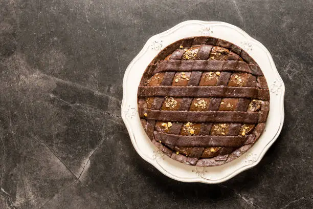 Chocolate Tart Pie Topped with Hazelnuts on Dark Stone Table Background