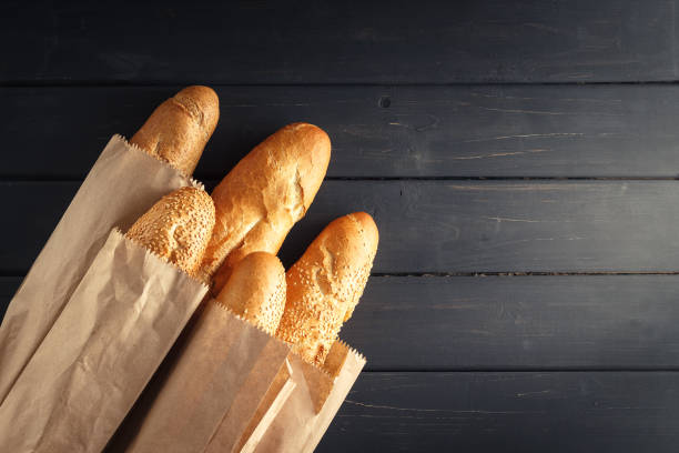 french baguettes with sesame seed on black wooden background - papel de pão imagens e fotografias de stock