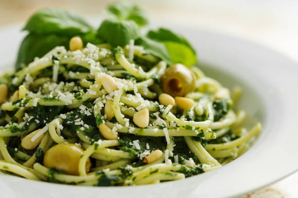 Tasty Beautiful Pasta Closeup with Spinach, Cheese, Olives, Basil and Nuts. stock photo