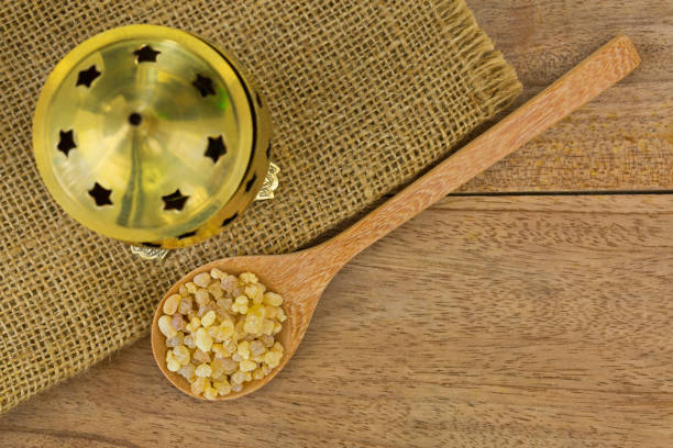 spoon of aromatic yellow resin gum next to brass incense burner on wood background - pyrolysis imagens e fotografias de stock