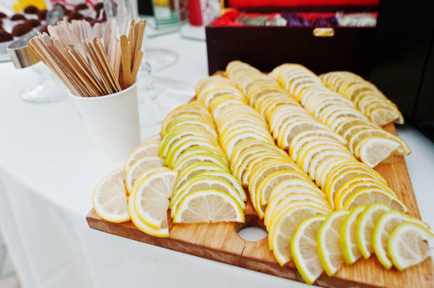 Cutted into slices lemon on wood board at wedding catering table.