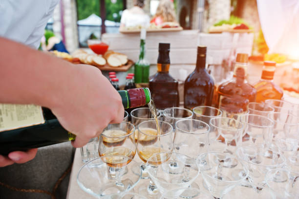 istock Hand of waiter who pours drinks at glasses on wedding reception. 660746318