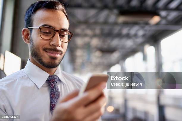 Indian Businessman Smiling Confidently And Surfing The Net On A Smartphone Stock Photo - Download Image Now