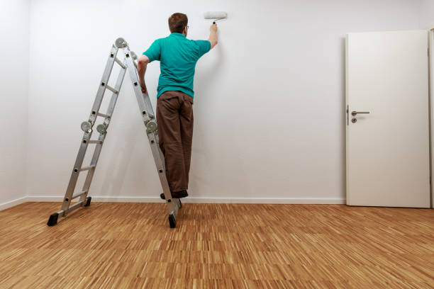 Man on ladder while painting the wall stock photo